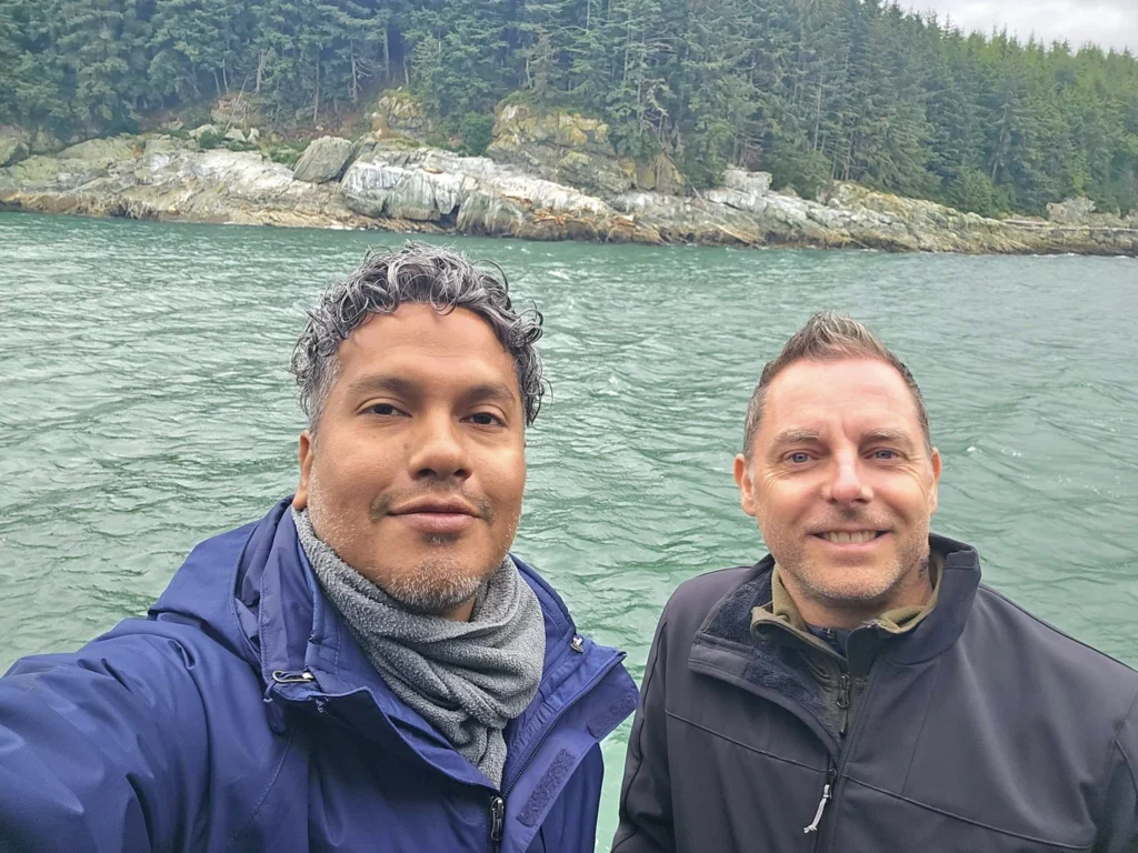 Cruising with Danny and Peter, Holland America Line, Westerdam, Juneau, Alaska, United States | Boat approaching Sentinel Island Lighthouse during Alaska whale watching tour, with humpback whale and stunning coastal scenery in the background.