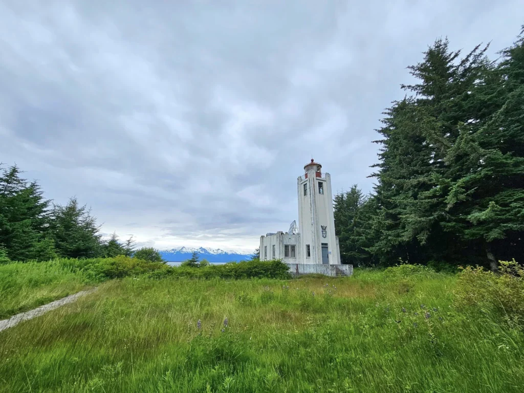 Cruising with Danny and Peter, Holland America Line, Westerdam, Juneau, Alaska, United States | Boat approaching Sentinel Island Lighthouse during Alaska whale watching tour, with humpback whale and stunning coastal scenery in the background.