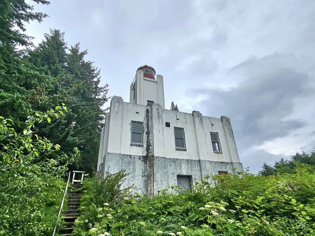 Cruising with Danny and Peter, Holland America Line, Westerdam, Juneau, Alaska, United States | Boat approaching Sentinel Island Lighthouse during Alaska whale watching tour, with humpback whale and stunning coastal scenery in the background.