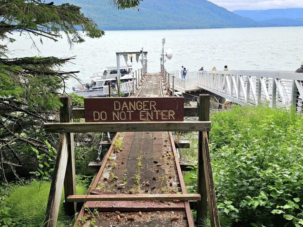 Cruising with Danny and Peter, Holland America Line, Westerdam, Juneau, Alaska, United States | Boat approaching Sentinel Island Lighthouse during Alaska whale watching tour, with humpback whale and stunning coastal scenery in the background.