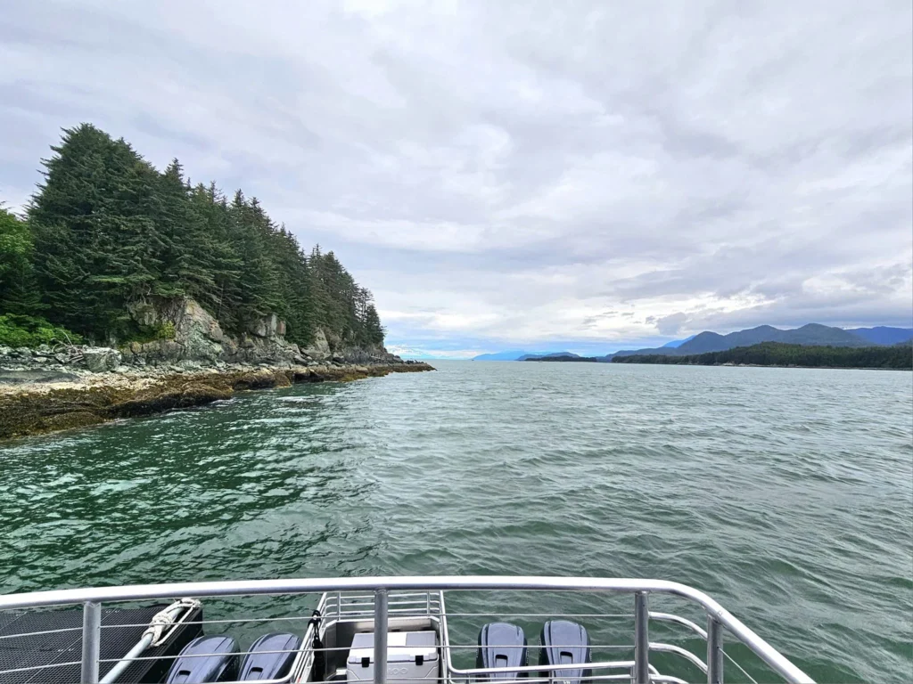 Cruising with Danny and Peter, Holland America Line, Westerdam, Juneau, Alaska, United States | Boat approaching Sentinel Island Lighthouse during Alaska whale watching tour, with humpback whale and stunning coastal scenery in the background.