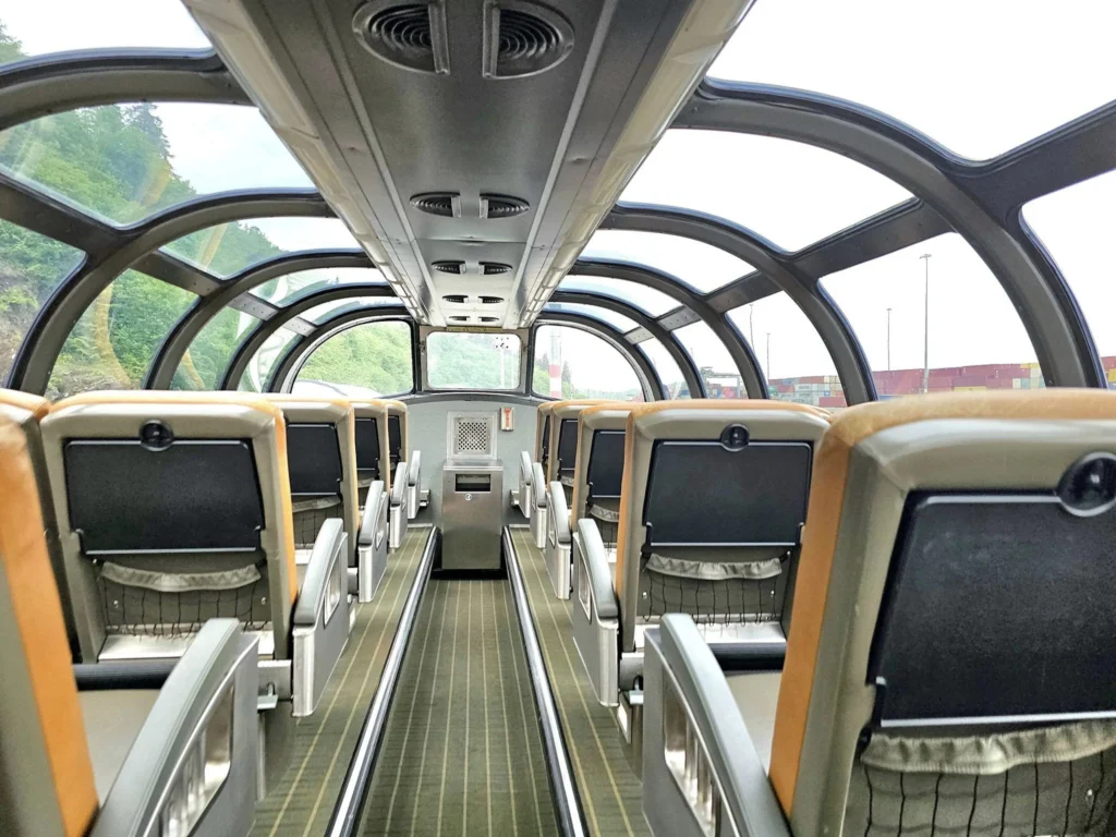 Cruising with Danny and Peter, Holland America Line, Westerdam, Prince Rupert, British Columbia, Canada | In the heart of British Columbia’s wild embrace, Where the Great Bear Rainforest weaves its mystic lace, A journey unfolds, both rail and road in stride, Through nature’s grandeur, where dreams and landscapes collide. From Prince Rupert’s charm, the train departs with grace, A serpentine path through forests’ ancient face, Panoramic windows frame a living, verdant dream, As the Skeena River’s flow whispers its serene theme. Mountains rise like giants, draped in emerald hues, While bald eagles soar, their shadows fleeting views, Black bears wander softly through the forest deep, And mountain goats on rugged cliffs silently leap. Kleanza Creek’s waterfalls cascade with a roar, Nature’s symphony on the rainforest’s floor, And Exchamsiks Park, a jewel of glacial light, Where shimmering pools reflect the day’s pure delight. From rail to road, the scenic drive unveils, A tapestry of mountains and verdant trails, Each turn a canvas painted with the wild’s own hand, A journey through a wonderland, vast and grand. Back in Prince Rupert, where history finds its place, The Museum’s treasures weave a cultural grace, Totem poles and masks tell tales of ancient lore, In this land where the past and present gently soar. Through the Great Bear Rainforest, we wandered wide, In rail and road’s embrace, where nature and culture collide, A journey of wonder, where memories are spun, In the heart of British Columbia, under the sun.