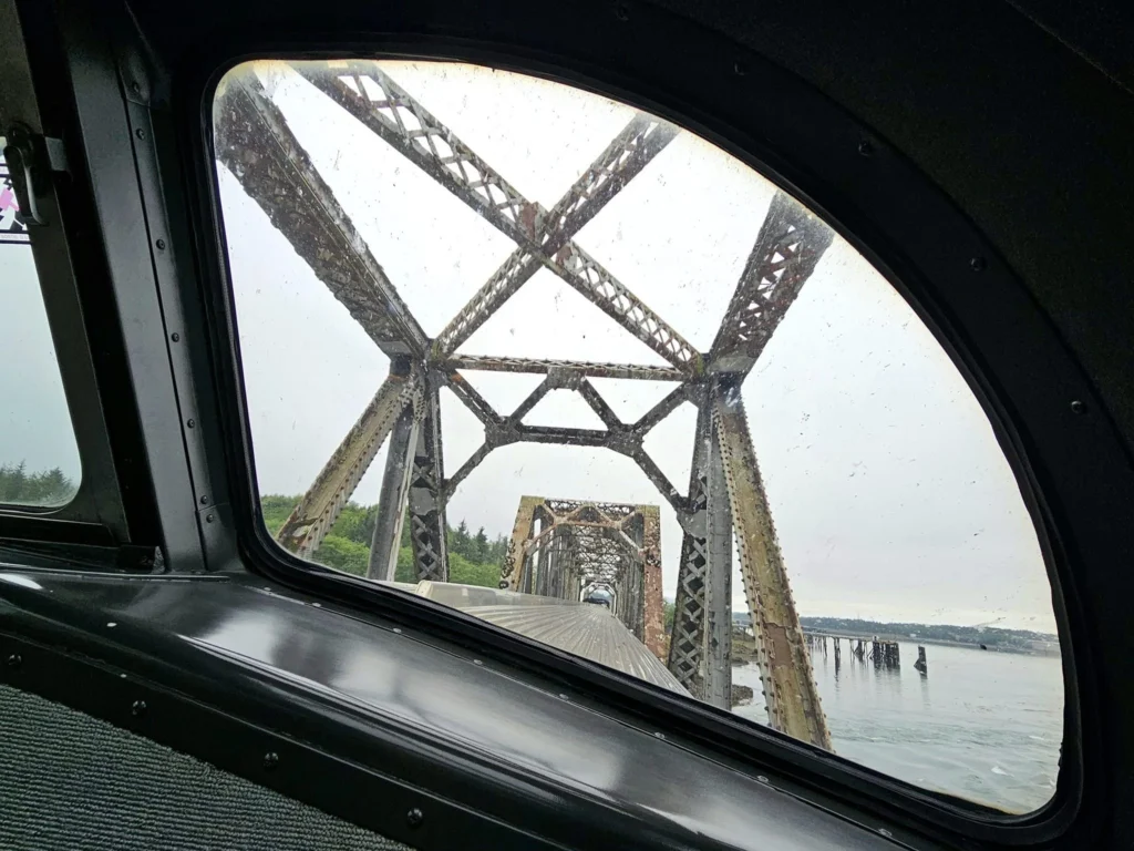 Cruising with Danny and Peter, Holland America Line, Westerdam, Prince Rupert, British Columbia, Canada | In the heart of British Columbia’s wild embrace, Where the Great Bear Rainforest weaves its mystic lace, A journey unfolds, both rail and road in stride, Through nature’s grandeur, where dreams and landscapes collide. From Prince Rupert’s charm, the train departs with grace, A serpentine path through forests’ ancient face, Panoramic windows frame a living, verdant dream, As the Skeena River’s flow whispers its serene theme. Mountains rise like giants, draped in emerald hues, While bald eagles soar, their shadows fleeting views, Black bears wander softly through the forest deep, And mountain goats on rugged cliffs silently leap. Kleanza Creek’s waterfalls cascade with a roar, Nature’s symphony on the rainforest’s floor, And Exchamsiks Park, a jewel of glacial light, Where shimmering pools reflect the day’s pure delight. From rail to road, the scenic drive unveils, A tapestry of mountains and verdant trails, Each turn a canvas painted with the wild’s own hand, A journey through a wonderland, vast and grand. Back in Prince Rupert, where history finds its place, The Museum’s treasures weave a cultural grace, Totem poles and masks tell tales of ancient lore, In this land where the past and present gently soar. Through the Great Bear Rainforest, we wandered wide, In rail and road’s embrace, where nature and culture collide, A journey of wonder, where memories are spun, In the heart of British Columbia, under the sun.