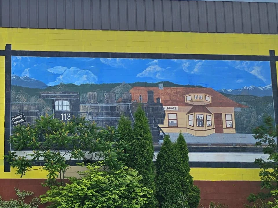 Cruising with Danny and Peter, Holland America Line, Westerdam, Prince Rupert, British Columbia, Canada | In the heart of British Columbia’s wild embrace, Where the Great Bear Rainforest weaves its mystic lace, A journey unfolds, both rail and road in stride, Through nature’s grandeur, where dreams and landscapes collide. From Prince Rupert’s charm, the train departs with grace, A serpentine path through forests’ ancient face, Panoramic windows frame a living, verdant dream, As the Skeena River’s flow whispers its serene theme. Mountains rise like giants, draped in emerald hues, While bald eagles soar, their shadows fleeting views, Black bears wander softly through the forest deep, And mountain goats on rugged cliffs silently leap. Kleanza Creek’s waterfalls cascade with a roar, Nature’s symphony on the rainforest’s floor, And Exchamsiks Park, a jewel of glacial light, Where shimmering pools reflect the day’s pure delight. From rail to road, the scenic drive unveils, A tapestry of mountains and verdant trails, Each turn a canvas painted with the wild’s own hand, A journey through a wonderland, vast and grand. Back in Prince Rupert, where history finds its place, The Museum’s treasures weave a cultural grace, Totem poles and masks tell tales of ancient lore, In this land where the past and present gently soar. Through the Great Bear Rainforest, we wandered wide, In rail and road’s embrace, where nature and culture collide, A journey of wonder, where memories are spun, In the heart of British Columbia, under the sun.