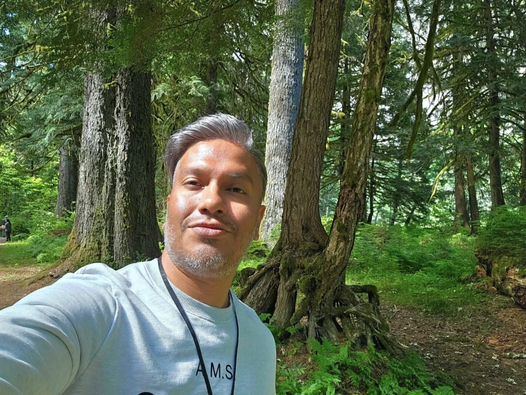 Cruising with Danny and Peter, Holland America Line, Westerdam, Prince Rupert, British Columbia, Canada | In the heart of British Columbia’s wild embrace, Where the Great Bear Rainforest weaves its mystic lace, A journey unfolds, both rail and road in stride, Through nature’s grandeur, where dreams and landscapes collide. From Prince Rupert’s charm, the train departs with grace, A serpentine path through forests’ ancient face, Panoramic windows frame a living, verdant dream, As the Skeena River’s flow whispers its serene theme. Mountains rise like giants, draped in emerald hues, While bald eagles soar, their shadows fleeting views, Black bears wander softly through the forest deep, And mountain goats on rugged cliffs silently leap. Kleanza Creek’s waterfalls cascade with a roar, Nature’s symphony on the rainforest’s floor, And Exchamsiks Park, a jewel of glacial light, Where shimmering pools reflect the day’s pure delight. From rail to road, the scenic drive unveils, A tapestry of mountains and verdant trails, Each turn a canvas painted with the wild’s own hand, A journey through a wonderland, vast and grand. Back in Prince Rupert, where history finds its place, The Museum’s treasures weave a cultural grace, Totem poles and masks tell tales of ancient lore, In this land where the past and present gently soar. Through the Great Bear Rainforest, we wandered wide, In rail and road’s embrace, where nature and culture collide, A journey of wonder, where memories are spun, In the heart of British Columbia, under the sun.