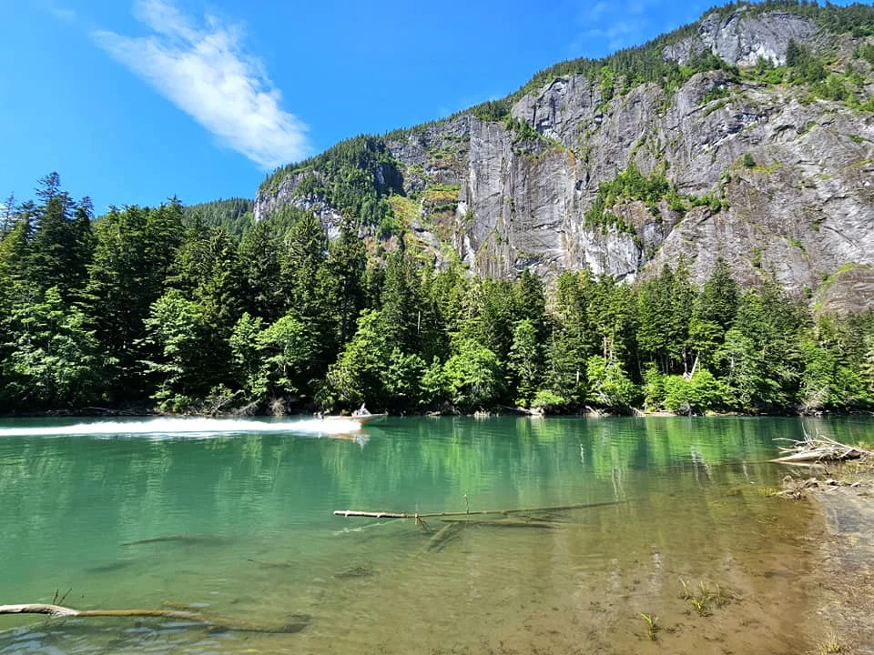 Cruising with Danny and Peter, Holland America Line, Westerdam, Prince Rupert, British Columbia, Canada | In the heart of British Columbia’s wild embrace, Where the Great Bear Rainforest weaves its mystic lace, A journey unfolds, both rail and road in stride, Through nature’s grandeur, where dreams and landscapes collide. From Prince Rupert’s charm, the train departs with grace, A serpentine path through forests’ ancient face, Panoramic windows frame a living, verdant dream, As the Skeena River’s flow whispers its serene theme. Mountains rise like giants, draped in emerald hues, While bald eagles soar, their shadows fleeting views, Black bears wander softly through the forest deep, And mountain goats on rugged cliffs silently leap. Kleanza Creek’s waterfalls cascade with a roar, Nature’s symphony on the rainforest’s floor, And Exchamsiks Park, a jewel of glacial light, Where shimmering pools reflect the day’s pure delight. From rail to road, the scenic drive unveils, A tapestry of mountains and verdant trails, Each turn a canvas painted with the wild’s own hand, A journey through a wonderland, vast and grand. Back in Prince Rupert, where history finds its place, The Museum’s treasures weave a cultural grace, Totem poles and masks tell tales of ancient lore, In this land where the past and present gently soar. Through the Great Bear Rainforest, we wandered wide, In rail and road’s embrace, where nature and culture collide, A journey of wonder, where memories are spun, In the heart of British Columbia, under the sun.