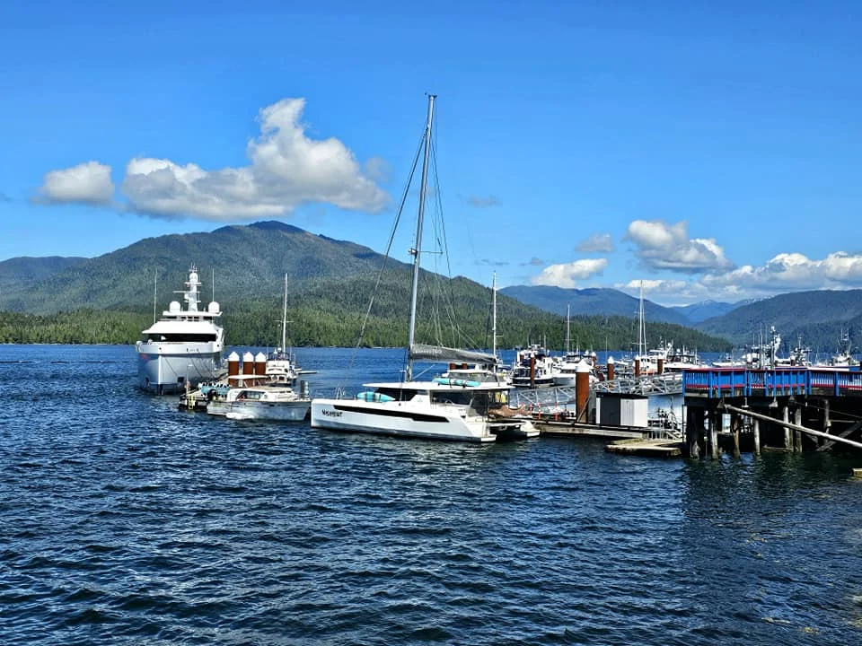 Cruising with Danny and Peter, Holland America Line, Westerdam, Prince Rupert, British Columbia, Canada | In the heart of British Columbia’s wild embrace, Where the Great Bear Rainforest weaves its mystic lace, A journey unfolds, both rail and road in stride, Through nature’s grandeur, where dreams and landscapes collide. From Prince Rupert’s charm, the train departs with grace, A serpentine path through forests’ ancient face, Panoramic windows frame a living, verdant dream, As the Skeena River’s flow whispers its serene theme. Mountains rise like giants, draped in emerald hues, While bald eagles soar, their shadows fleeting views, Black bears wander softly through the forest deep, And mountain goats on rugged cliffs silently leap. Kleanza Creek’s waterfalls cascade with a roar, Nature’s symphony on the rainforest’s floor, And Exchamsiks Park, a jewel of glacial light, Where shimmering pools reflect the day’s pure delight. From rail to road, the scenic drive unveils, A tapestry of mountains and verdant trails, Each turn a canvas painted with the wild’s own hand, A journey through a wonderland, vast and grand. Back in Prince Rupert, where history finds its place, The Museum’s treasures weave a cultural grace, Totem poles and masks tell tales of ancient lore, In this land where the past and present gently soar. Through the Great Bear Rainforest, we wandered wide, In rail and road’s embrace, where nature and culture collide, A journey of wonder, where memories are spun, In the heart of British Columbia, under the sun.
