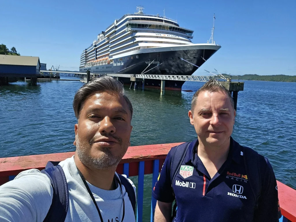 Cruising with Danny and Peter, Holland America Line, Westerdam, Prince Rupert, British Columbia, Canada | In the heart of British Columbia’s wild embrace, Where the Great Bear Rainforest weaves its mystic lace, A journey unfolds, both rail and road in stride, Through nature’s grandeur, where dreams and landscapes collide. From Prince Rupert’s charm, the train departs with grace, A serpentine path through forests’ ancient face, Panoramic windows frame a living, verdant dream, As the Skeena River’s flow whispers its serene theme. Mountains rise like giants, draped in emerald hues, While bald eagles soar, their shadows fleeting views, Black bears wander softly through the forest deep, And mountain goats on rugged cliffs silently leap. Kleanza Creek’s waterfalls cascade with a roar, Nature’s symphony on the rainforest’s floor, And Exchamsiks Park, a jewel of glacial light, Where shimmering pools reflect the day’s pure delight. From rail to road, the scenic drive unveils, A tapestry of mountains and verdant trails, Each turn a canvas painted with the wild’s own hand, A journey through a wonderland, vast and grand. Back in Prince Rupert, where history finds its place, The Museum’s treasures weave a cultural grace, Totem poles and masks tell tales of ancient lore, In this land where the past and present gently soar. Through the Great Bear Rainforest, we wandered wide, In rail and road’s embrace, where nature and culture collide, A journey of wonder, where memories are spun, In the heart of British Columbia, under the sun.