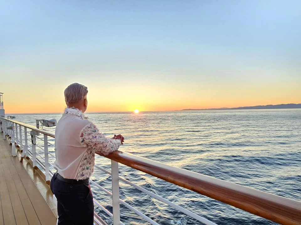Cruising with Danny and Peter, Holland America Line, Westerdam, Seattle, Washington, United States | Stunning sunset over the ocean during a magical evening cruise from Prince Rupert on the Westerdam, with vibrant orange and pink skies reflecting on calm waters.