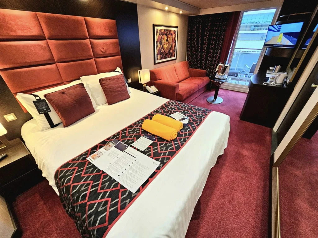 Cruising with Danny and Peter, MSC Cruises, MSC Preziosa, Rotterdam, The Netherlands, Birthday Cruise | The majestic MSC Preziosa cruise ship docked at Rotterdam’s Cruise Terminal on Wilhelminakade, its sleek white exterior gleaming against the modern city skyline with the iconic Erasmus Bridge in the background. Passengers board for a Northern Europe mini-cruise, celebrating a birthday with luxurious touches like a chilled bottle of Spumante and macarons in a stylish cabin. The vibrant onboard atmosphere features a gourmet dining experience at Butcher’s Cut Chef’s Table with a surprise birthday cake, thrilling entertainment at the Platinum Theater’s Rock Nation show with singers and dancers, and a lively Silent Disco in the Safari Lounge. The scene captures the excitement of embarkation day, with scenic views of Rotterdam’s waterfront, onboard shopping for MSC souvenirs, and the promise of an unforgettable luxury cruise vacation.