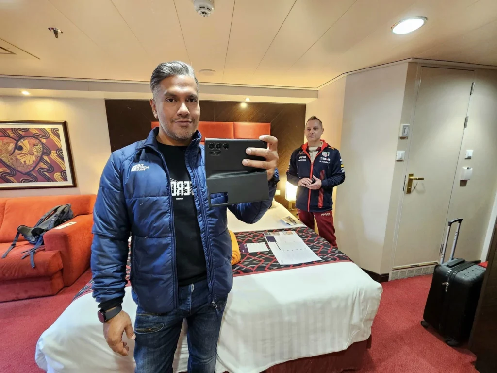 Cruising with Danny and Peter, MSC Cruises, MSC Preziosa, Rotterdam, The Netherlands, Birthday Cruise | The majestic MSC Preziosa cruise ship docked at Rotterdam’s Cruise Terminal on Wilhelminakade, its sleek white exterior gleaming against the modern city skyline with the iconic Erasmus Bridge in the background. Passengers board for a Northern Europe mini-cruise, celebrating a birthday with luxurious touches like a chilled bottle of Spumante and macarons in a stylish cabin. The vibrant onboard atmosphere features a gourmet dining experience at Butcher’s Cut Chef’s Table with a surprise birthday cake, thrilling entertainment at the Platinum Theater’s Rock Nation show with singers and dancers, and a lively Silent Disco in the Safari Lounge. The scene captures the excitement of embarkation day, with scenic views of Rotterdam’s waterfront, onboard shopping for MSC souvenirs, and the promise of an unforgettable luxury cruise vacation.