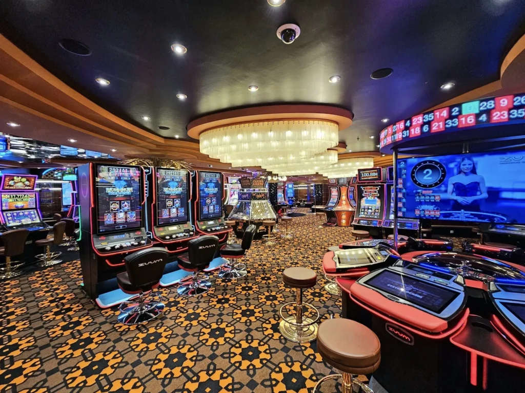 Cruising with Danny and Peter, MSC Cruises, MSC Preziosa, Rotterdam, The Netherlands, Birthday Cruise | The majestic MSC Preziosa cruise ship docked at Rotterdam’s Cruise Terminal on Wilhelminakade, its sleek white exterior gleaming against the modern city skyline with the iconic Erasmus Bridge in the background. Passengers board for a Northern Europe mini-cruise, celebrating a birthday with luxurious touches like a chilled bottle of Spumante and macarons in a stylish cabin. The vibrant onboard atmosphere features a gourmet dining experience at Butcher’s Cut Chef’s Table with a surprise birthday cake, thrilling entertainment at the Platinum Theater’s Rock Nation show with singers and dancers, and a lively Silent Disco in the Safari Lounge. The scene captures the excitement of embarkation day, with scenic views of Rotterdam’s waterfront, onboard shopping for MSC souvenirs, and the promise of an unforgettable luxury cruise vacation.