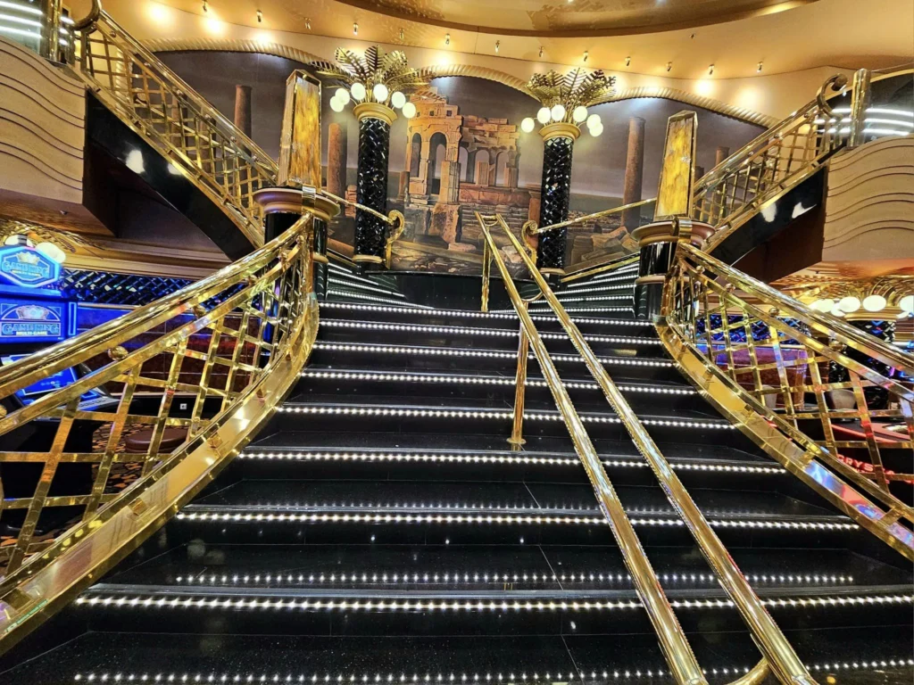 Cruising with Danny and Peter, MSC Cruises, MSC Preziosa, Rotterdam, The Netherlands, Birthday Cruise | The majestic MSC Preziosa cruise ship docked at Rotterdam’s Cruise Terminal on Wilhelminakade, its sleek white exterior gleaming against the modern city skyline with the iconic Erasmus Bridge in the background. Passengers board for a Northern Europe mini-cruise, celebrating a birthday with luxurious touches like a chilled bottle of Spumante and macarons in a stylish cabin. The vibrant onboard atmosphere features a gourmet dining experience at Butcher’s Cut Chef’s Table with a surprise birthday cake, thrilling entertainment at the Platinum Theater’s Rock Nation show with singers and dancers, and a lively Silent Disco in the Safari Lounge. The scene captures the excitement of embarkation day, with scenic views of Rotterdam’s waterfront, onboard shopping for MSC souvenirs, and the promise of an unforgettable luxury cruise vacation.