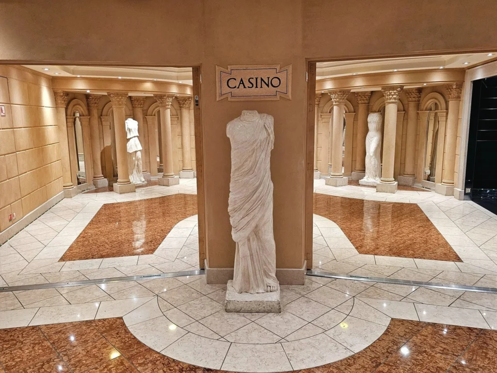 Cruising with Danny and Peter, MSC Cruises, MSC Preziosa, Rotterdam, The Netherlands, Birthday Cruise | The majestic MSC Preziosa cruise ship docked at Rotterdam’s Cruise Terminal on Wilhelminakade, its sleek white exterior gleaming against the modern city skyline with the iconic Erasmus Bridge in the background. Passengers board for a Northern Europe mini-cruise, celebrating a birthday with luxurious touches like a chilled bottle of Spumante and macarons in a stylish cabin. The vibrant onboard atmosphere features a gourmet dining experience at Butcher’s Cut Chef’s Table with a surprise birthday cake, thrilling entertainment at the Platinum Theater’s Rock Nation show with singers and dancers, and a lively Silent Disco in the Safari Lounge. The scene captures the excitement of embarkation day, with scenic views of Rotterdam’s waterfront, onboard shopping for MSC souvenirs, and the promise of an unforgettable luxury cruise vacation.