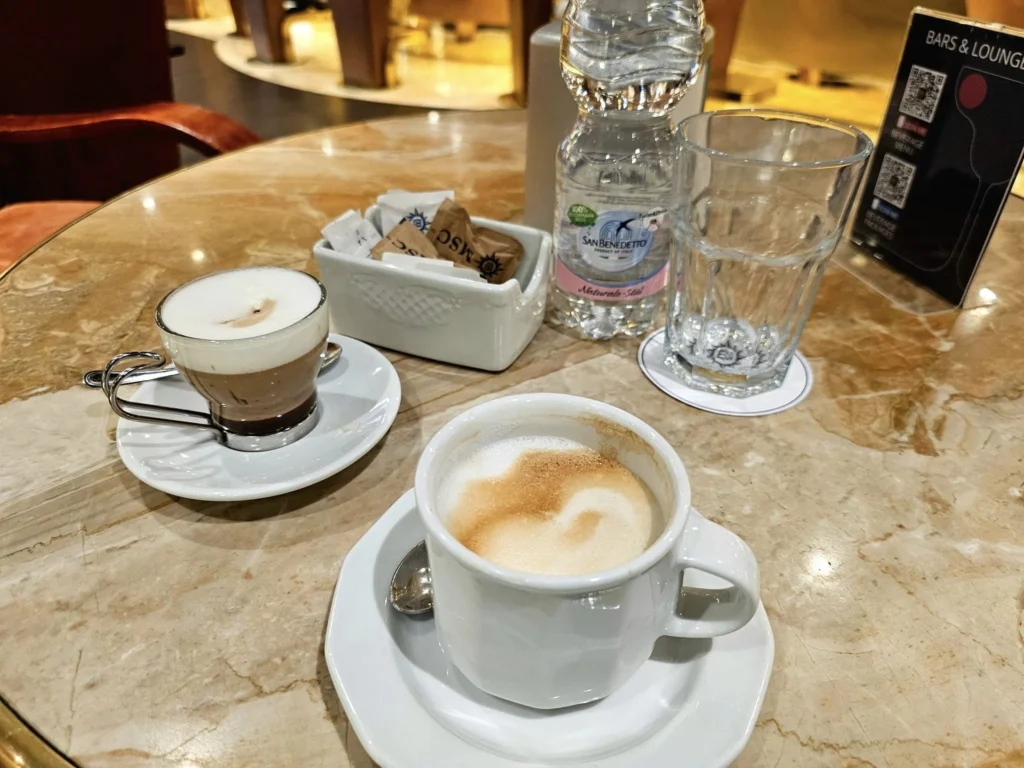 Cruising with Danny and Peter, MSC Cruises, MSC Preziosa, Rotterdam, The Netherlands, Birthday Cruise | The majestic MSC Preziosa cruise ship docked at Rotterdam’s Cruise Terminal on Wilhelminakade, its sleek white exterior gleaming against the modern city skyline with the iconic Erasmus Bridge in the background. Passengers board for a Northern Europe mini-cruise, celebrating a birthday with luxurious touches like a chilled bottle of Spumante and macarons in a stylish cabin. The vibrant onboard atmosphere features a gourmet dining experience at Butcher’s Cut Chef’s Table with a surprise birthday cake, thrilling entertainment at the Platinum Theater’s Rock Nation show with singers and dancers, and a lively Silent Disco in the Safari Lounge. The scene captures the excitement of embarkation day, with scenic views of Rotterdam’s waterfront, onboard shopping for MSC souvenirs, and the promise of an unforgettable luxury cruise vacation.