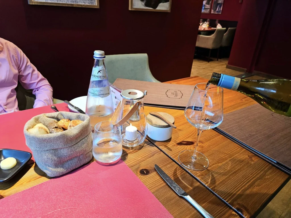 Cruising with Danny and Peter, MSC Cruises, MSC Preziosa, Rotterdam, The Netherlands, Birthday Cruise | The majestic MSC Preziosa cruise ship docked at Rotterdam’s Cruise Terminal on Wilhelminakade, its sleek white exterior gleaming against the modern city skyline with the iconic Erasmus Bridge in the background. Passengers board for a Northern Europe mini-cruise, celebrating a birthday with luxurious touches like a chilled bottle of Spumante and macarons in a stylish cabin. The vibrant onboard atmosphere features a gourmet dining experience at Butcher’s Cut Chef’s Table with a surprise birthday cake, thrilling entertainment at the Platinum Theater’s Rock Nation show with singers and dancers, and a lively Silent Disco in the Safari Lounge. The scene captures the excitement of embarkation day, with scenic views of Rotterdam’s waterfront, onboard shopping for MSC souvenirs, and the promise of an unforgettable luxury cruise vacation.