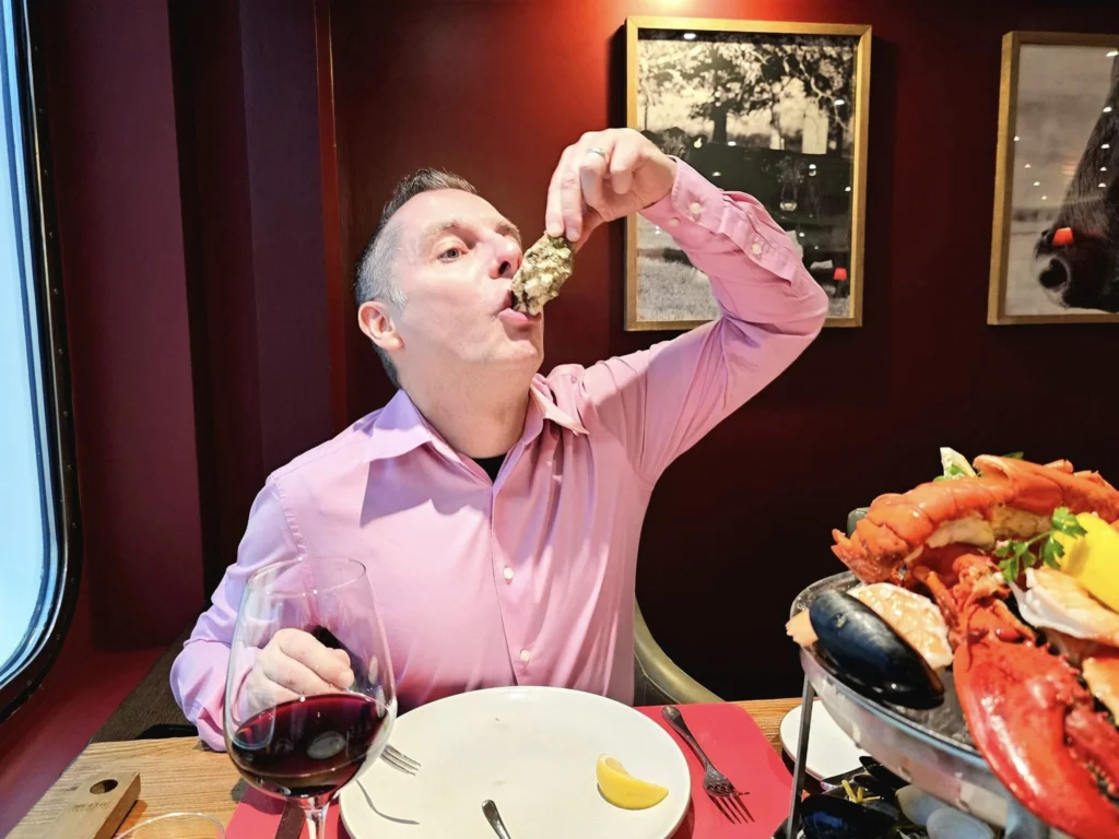 Cruising with Danny and Peter, MSC Cruises, MSC Preziosa, Rotterdam, The Netherlands, Birthday Cruise | The majestic MSC Preziosa cruise ship docked at Rotterdam’s Cruise Terminal on Wilhelminakade, its sleek white exterior gleaming against the modern city skyline with the iconic Erasmus Bridge in the background. Passengers board for a Northern Europe mini-cruise, celebrating a birthday with luxurious touches like a chilled bottle of Spumante and macarons in a stylish cabin. The vibrant onboard atmosphere features a gourmet dining experience at Butcher’s Cut Chef’s Table with a surprise birthday cake, thrilling entertainment at the Platinum Theater’s Rock Nation show with singers and dancers, and a lively Silent Disco in the Safari Lounge. The scene captures the excitement of embarkation day, with scenic views of Rotterdam’s waterfront, onboard shopping for MSC souvenirs, and the promise of an unforgettable luxury cruise vacation.