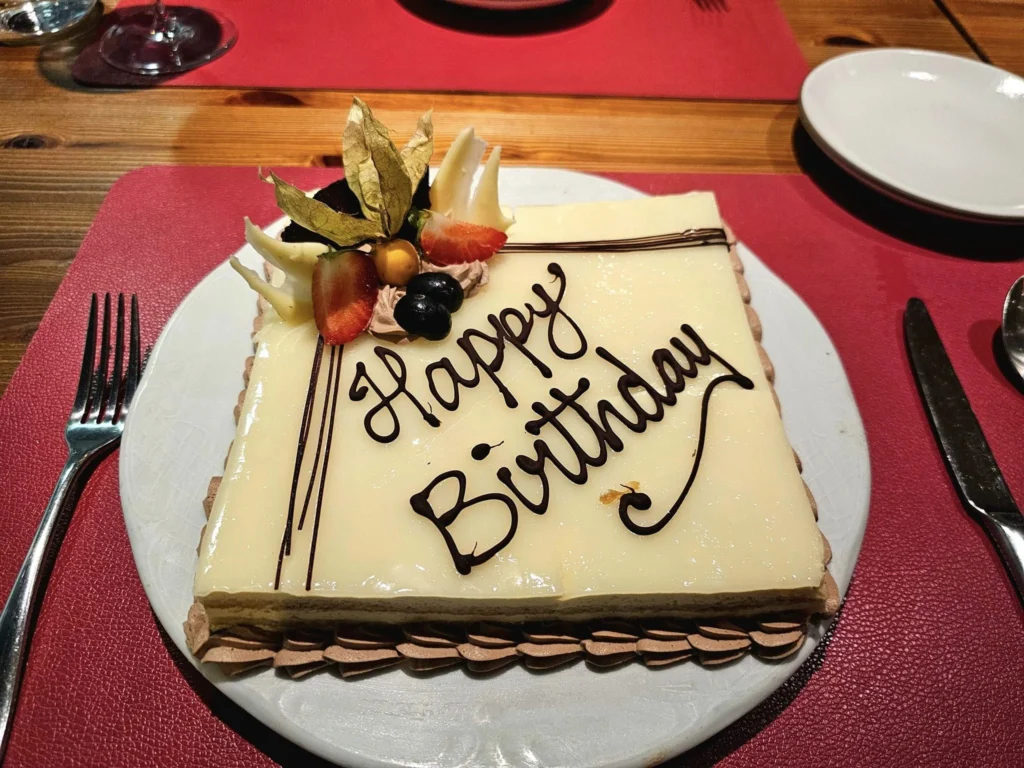 Cruising with Danny and Peter, MSC Cruises, MSC Preziosa, Rotterdam, The Netherlands, Birthday Cruise | The majestic MSC Preziosa cruise ship docked at Rotterdam’s Cruise Terminal on Wilhelminakade, its sleek white exterior gleaming against the modern city skyline with the iconic Erasmus Bridge in the background. Passengers board for a Northern Europe mini-cruise, celebrating a birthday with luxurious touches like a chilled bottle of Spumante and macarons in a stylish cabin. The vibrant onboard atmosphere features a gourmet dining experience at Butcher’s Cut Chef’s Table with a surprise birthday cake, thrilling entertainment at the Platinum Theater’s Rock Nation show with singers and dancers, and a lively Silent Disco in the Safari Lounge. The scene captures the excitement of embarkation day, with scenic views of Rotterdam’s waterfront, onboard shopping for MSC souvenirs, and the promise of an unforgettable luxury cruise vacation.