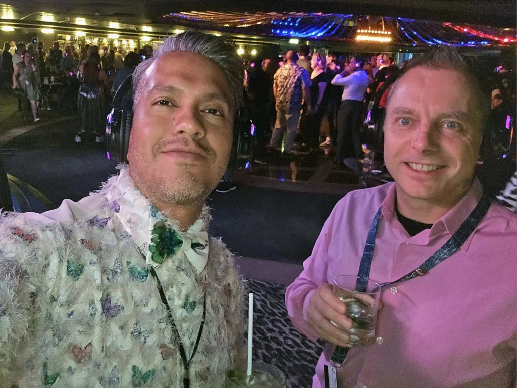 Cruising with Danny and Peter, MSC Cruises, MSC Preziosa, Rotterdam, The Netherlands, Birthday Cruise | The majestic MSC Preziosa cruise ship docked at Rotterdam’s Cruise Terminal on Wilhelminakade, its sleek white exterior gleaming against the modern city skyline with the iconic Erasmus Bridge in the background. Passengers board for a Northern Europe mini-cruise, celebrating a birthday with luxurious touches like a chilled bottle of Spumante and macarons in a stylish cabin. The vibrant onboard atmosphere features a gourmet dining experience at Butcher’s Cut Chef’s Table with a surprise birthday cake, thrilling entertainment at the Platinum Theater’s Rock Nation show with singers and dancers, and a lively Silent Disco in the Safari Lounge. The scene captures the excitement of embarkation day, with scenic views of Rotterdam’s waterfront, onboard shopping for MSC souvenirs, and the promise of an unforgettable luxury cruise vacation.