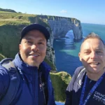 Cruising with Danny and Peter, MSC Cruises, MSC Preziosa, Le Havre, Paris, Étretat, France | Stunning views of the Étretat natural arches against the Normandy coastline, featuring the iconic L'Aiguille rock formation, picturesque half-timbered houses in Étretat, and travelers enjoying scenic walks along the cliffs during the unguided tour from MSC Preziosa.