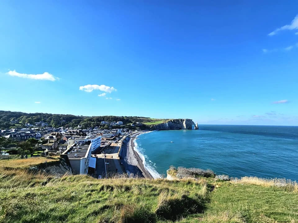Cruising with Danny and Peter, MSC Cruises, MSC Preziosa, Le Havre, Paris, Étretat, France | Stunning views of the Étretat natural arches against the Normandy coastline, featuring the iconic L'Aiguille rock formation, picturesque half-timbered houses in Étretat, and travelers enjoying scenic walks along the cliffs during the unguided tour from MSC Preziosa.