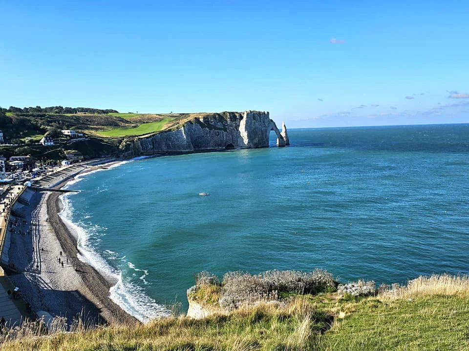 Cruising with Danny and Peter, MSC Cruises, MSC Preziosa, Le Havre, Paris, Étretat, France | Stunning views of the Étretat natural arches against the Normandy coastline, featuring the iconic L'Aiguille rock formation, picturesque half-timbered houses in Étretat, and travelers enjoying scenic walks along the cliffs during the unguided tour from MSC Preziosa.