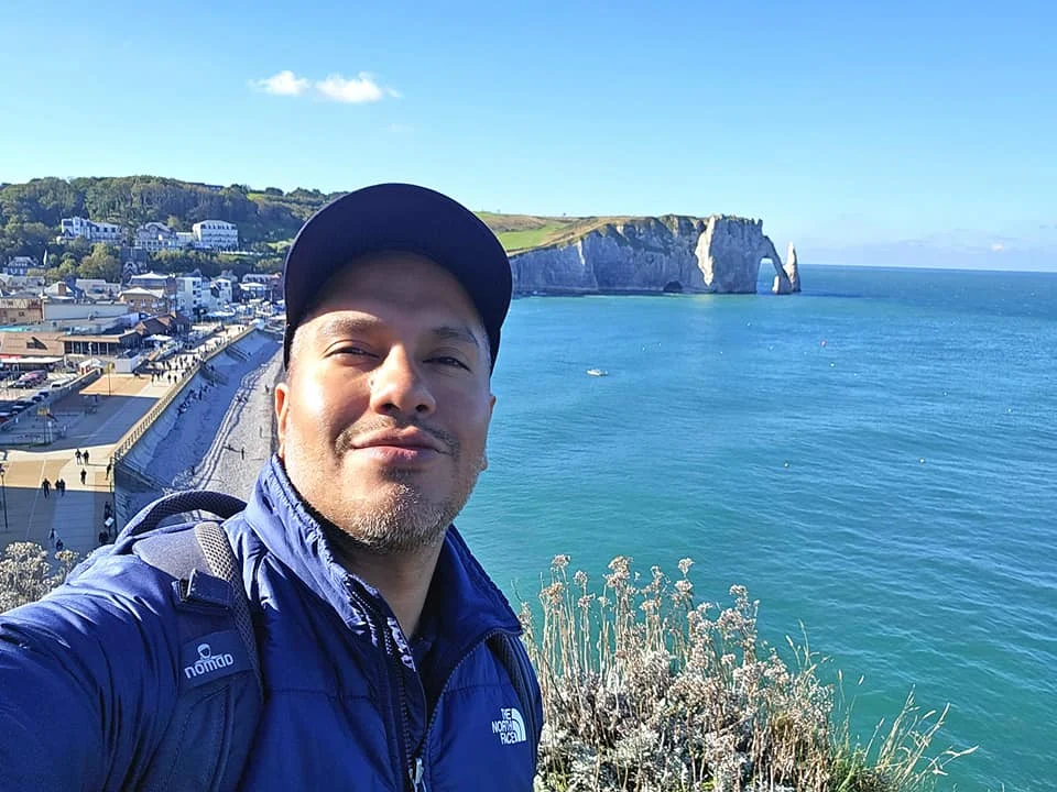 Cruising with Danny and Peter, MSC Cruises, MSC Preziosa, Le Havre, Paris, Étretat, France | Stunning views of the Étretat natural arches against the Normandy coastline, featuring the iconic L'Aiguille rock formation, picturesque half-timbered houses in Étretat, and travelers enjoying scenic walks along the cliffs during the unguided tour from MSC Preziosa.