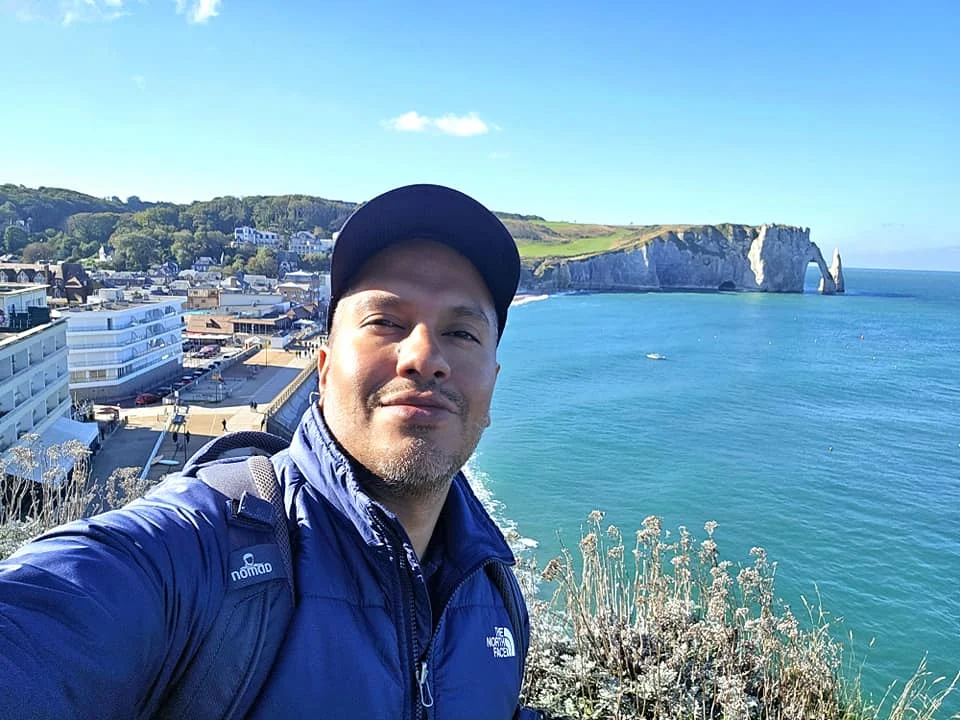 Cruising with Danny and Peter, MSC Cruises, MSC Preziosa, Le Havre, Paris, Étretat, France | Stunning views of the Étretat natural arches against the Normandy coastline, featuring the iconic L'Aiguille rock formation, picturesque half-timbered houses in Étretat, and travelers enjoying scenic walks along the cliffs during the unguided tour from MSC Preziosa.