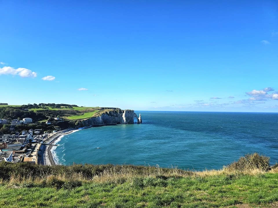 Cruising with Danny and Peter, MSC Cruises, MSC Preziosa, Le Havre, Paris, Étretat, France | Stunning views of the Étretat natural arches against the Normandy coastline, featuring the iconic L'Aiguille rock formation, picturesque half-timbered houses in Étretat, and travelers enjoying scenic walks along the cliffs during the unguided tour from MSC Preziosa.
