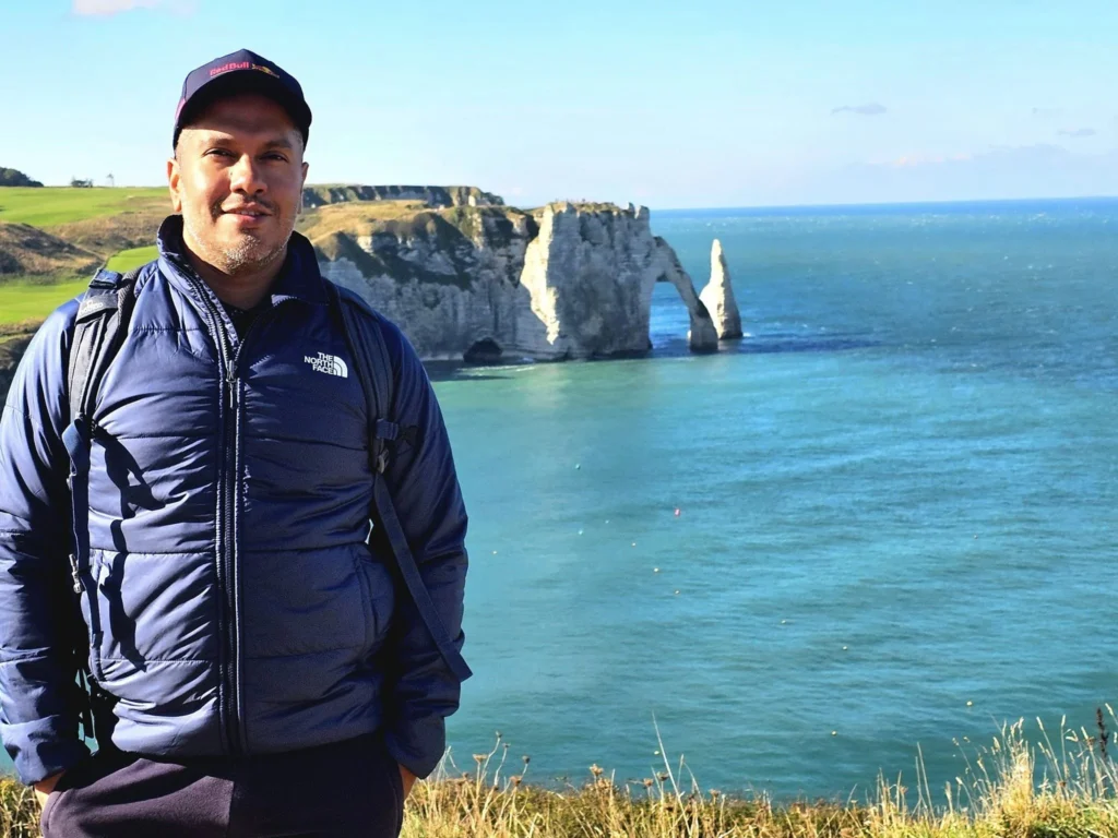 Cruising with Danny and Peter, MSC Cruises, MSC Preziosa, Le Havre, Paris, Étretat, France | Stunning views of the Étretat natural arches against the Normandy coastline, featuring the iconic L'Aiguille rock formation, picturesque half-timbered houses in Étretat, and travelers enjoying scenic walks along the cliffs during the unguided tour from MSC Preziosa.