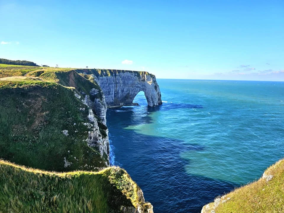 Cruising with Danny and Peter, MSC Cruises, MSC Preziosa, Le Havre, Paris, Étretat, France | Stunning views of the Étretat natural arches against the Normandy coastline, featuring the iconic L'Aiguille rock formation, picturesque half-timbered houses in Étretat, and travelers enjoying scenic walks along the cliffs during the unguided tour from MSC Preziosa.