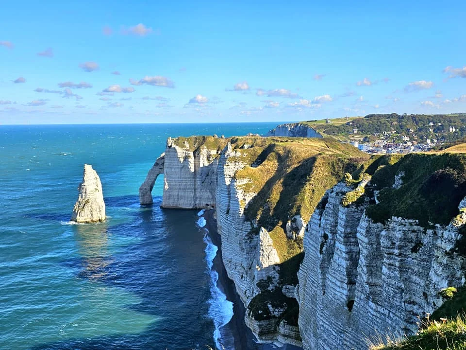 Cruising with Danny and Peter, MSC Cruises, MSC Preziosa, Le Havre, Paris, Étretat, France | Stunning views of the Étretat natural arches against the Normandy coastline, featuring the iconic L'Aiguille rock formation, picturesque half-timbered houses in Étretat, and travelers enjoying scenic walks along the cliffs during the unguided tour from MSC Preziosa.