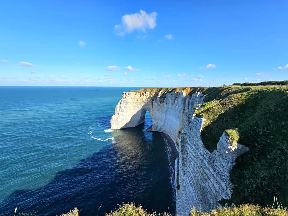 Cruising with Danny and Peter, MSC Cruises, MSC Preziosa, Le Havre, Paris, Étretat, France | Stunning views of the Étretat natural arches against the Normandy coastline, featuring the iconic L'Aiguille rock formation, picturesque half-timbered houses in Étretat, and travelers enjoying scenic walks along the cliffs during the unguided tour from MSC Preziosa.
