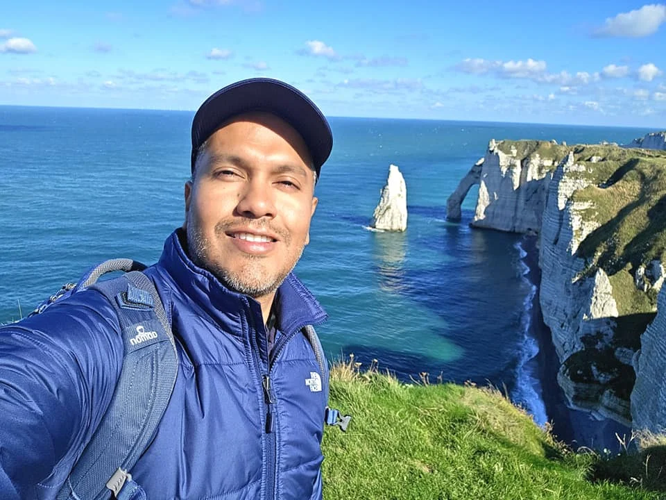 Cruising with Danny and Peter, MSC Cruises, MSC Preziosa, Le Havre, Paris, Étretat, France | Stunning views of the Étretat natural arches against the Normandy coastline, featuring the iconic L'Aiguille rock formation, picturesque half-timbered houses in Étretat, and travelers enjoying scenic walks along the cliffs during the unguided tour from MSC Preziosa.