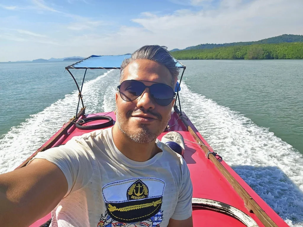 Cruising with Danny and Peter, Holland America Line, Westerdam, Phuket, Thailand | Longtail boat navigating clear waters near James Bond Island, showcasing iconic limestone cliffs. Enjoy dining at a floating restaurant on Phang Nga Bay, kayaking through lush mangroves, and exploring hidden caves with unique rock formations during an unforgettable Phuket island tour.