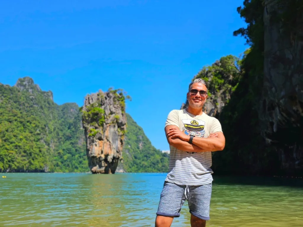Cruising with Danny and Peter, Holland America Line, Westerdam, Phuket, Thailand | Longtail boat navigating clear waters near James Bond Island, showcasing iconic limestone cliffs. Enjoy dining at a floating restaurant on Phang Nga Bay, kayaking through lush mangroves, and exploring hidden caves with unique rock formations during an unforgettable Phuket island tour.