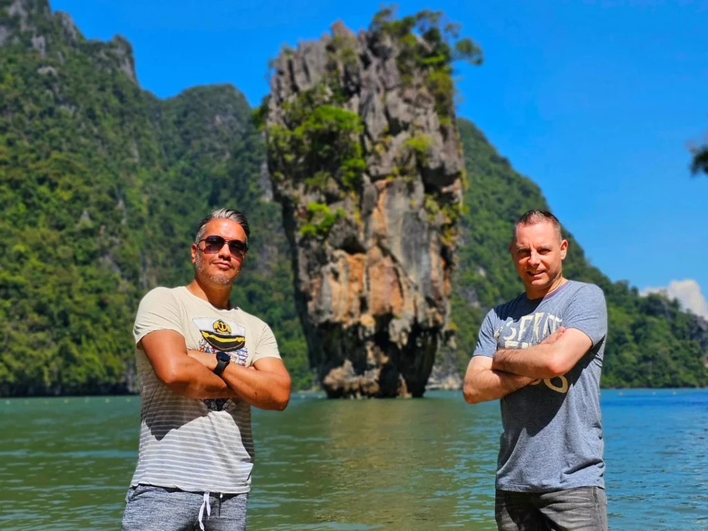 Cruising with Danny and Peter, Holland America Line, Westerdam, Phuket, Thailand | Longtail boat navigating clear waters near James Bond Island, showcasing iconic limestone cliffs. Enjoy dining at a floating restaurant on Phang Nga Bay, kayaking through lush mangroves, and exploring hidden caves with unique rock formations during an unforgettable Phuket island tour.