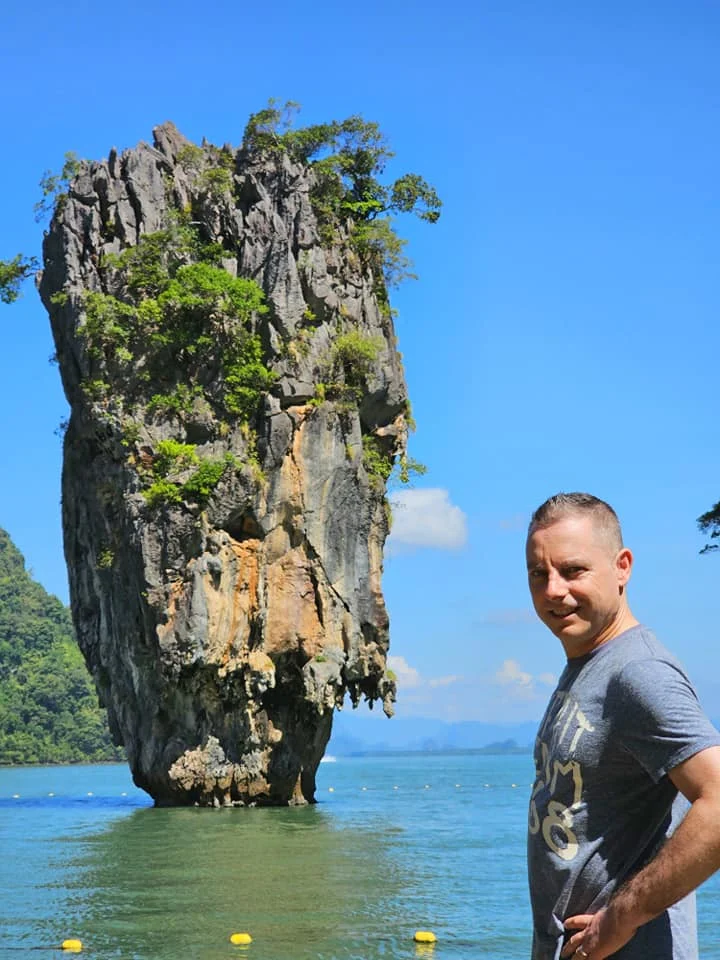 Cruising with Danny and Peter, Holland America Line, Westerdam, Phuket, Thailand | Longtail boat navigating clear waters near James Bond Island, showcasing iconic limestone cliffs. Enjoy dining at a floating restaurant on Phang Nga Bay, kayaking through lush mangroves, and exploring hidden caves with unique rock formations during an unforgettable Phuket island tour.