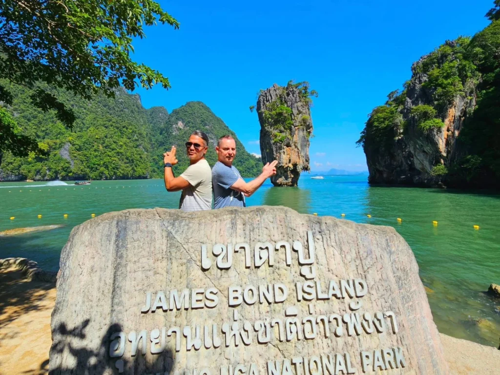 Cruising with Danny and Peter, Holland America Line, Westerdam, Phuket, Thailand | Longtail boat navigating clear waters near James Bond Island, showcasing iconic limestone cliffs. Enjoy dining at a floating restaurant on Phang Nga Bay, kayaking through lush mangroves, and exploring hidden caves with unique rock formations during an unforgettable Phuket island tour.