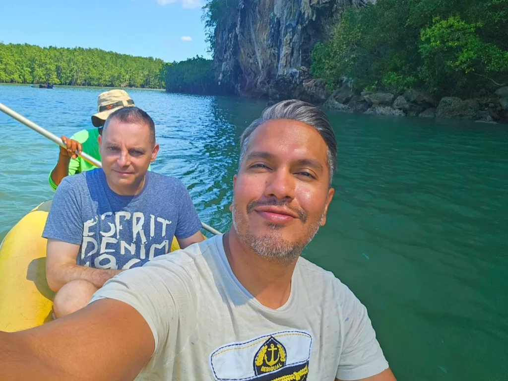Cruising with Danny and Peter, Holland America Line, Westerdam, Phuket, Thailand | Longtail boat navigating clear waters near James Bond Island, showcasing iconic limestone cliffs. Enjoy dining at a floating restaurant on Phang Nga Bay, kayaking through lush mangroves, and exploring hidden caves with unique rock formations during an unforgettable Phuket island tour.
