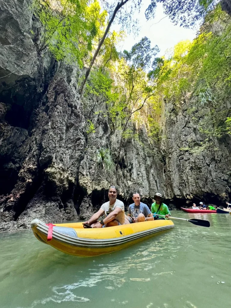 Cruising with Danny and Peter, Holland America Line, Westerdam, Phuket, Thailand | Longtail boat navigating clear waters near James Bond Island, showcasing iconic limestone cliffs. Enjoy dining at a floating restaurant on Phang Nga Bay, kayaking through lush mangroves, and exploring hidden caves with unique rock formations during an unforgettable Phuket island tour.