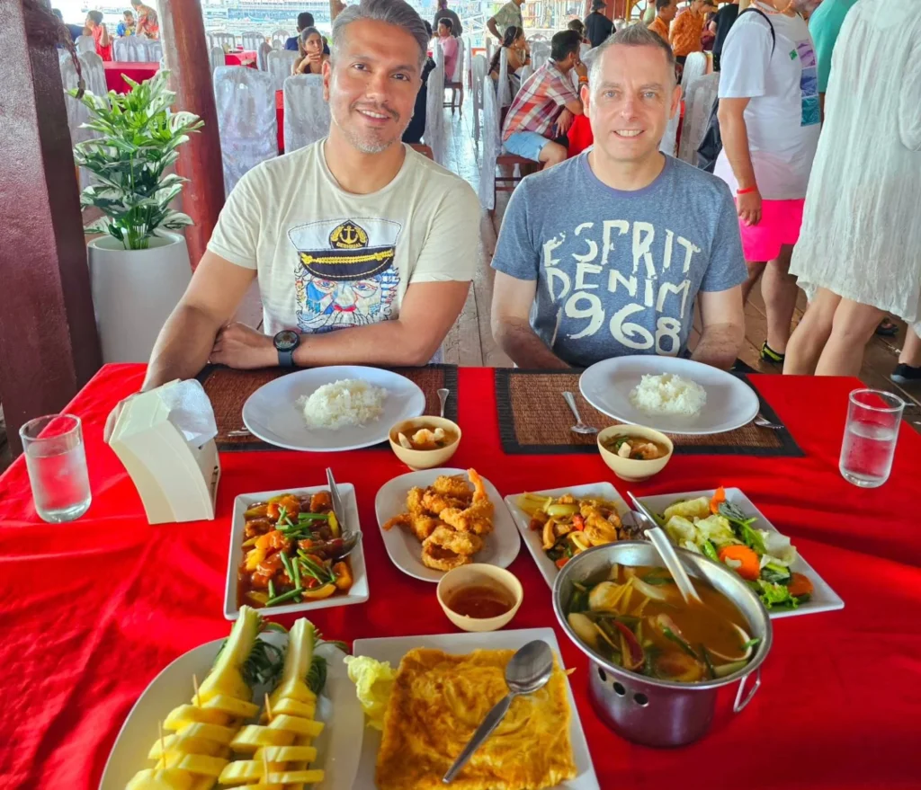 Cruising with Danny and Peter, Holland America Line, Westerdam, Phuket, Thailand | Longtail boat navigating clear waters near James Bond Island, showcasing iconic limestone cliffs. Enjoy dining at a floating restaurant on Phang Nga Bay, kayaking through lush mangroves, and exploring hidden caves with unique rock formations during an unforgettable Phuket island tour.