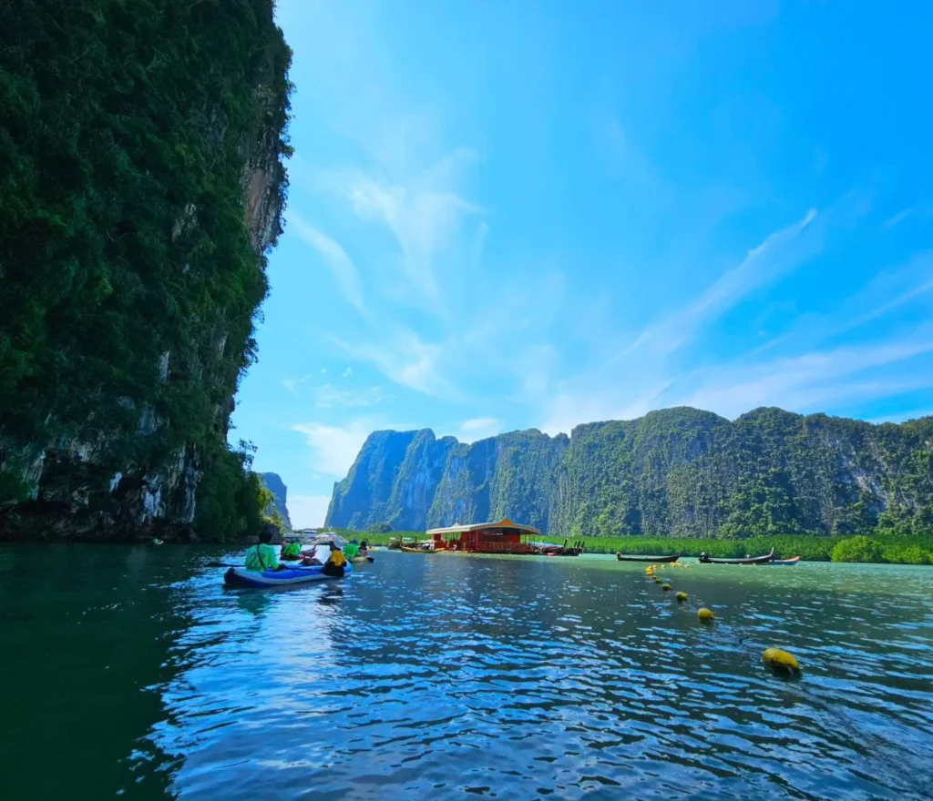 Cruising with Danny and Peter, Holland America Line, Westerdam, Phuket, Thailand | Longtail boat navigating clear waters near James Bond Island, showcasing iconic limestone cliffs. Enjoy dining at a floating restaurant on Phang Nga Bay, kayaking through lush mangroves, and exploring hidden caves with unique rock formations during an unforgettable Phuket island tour.