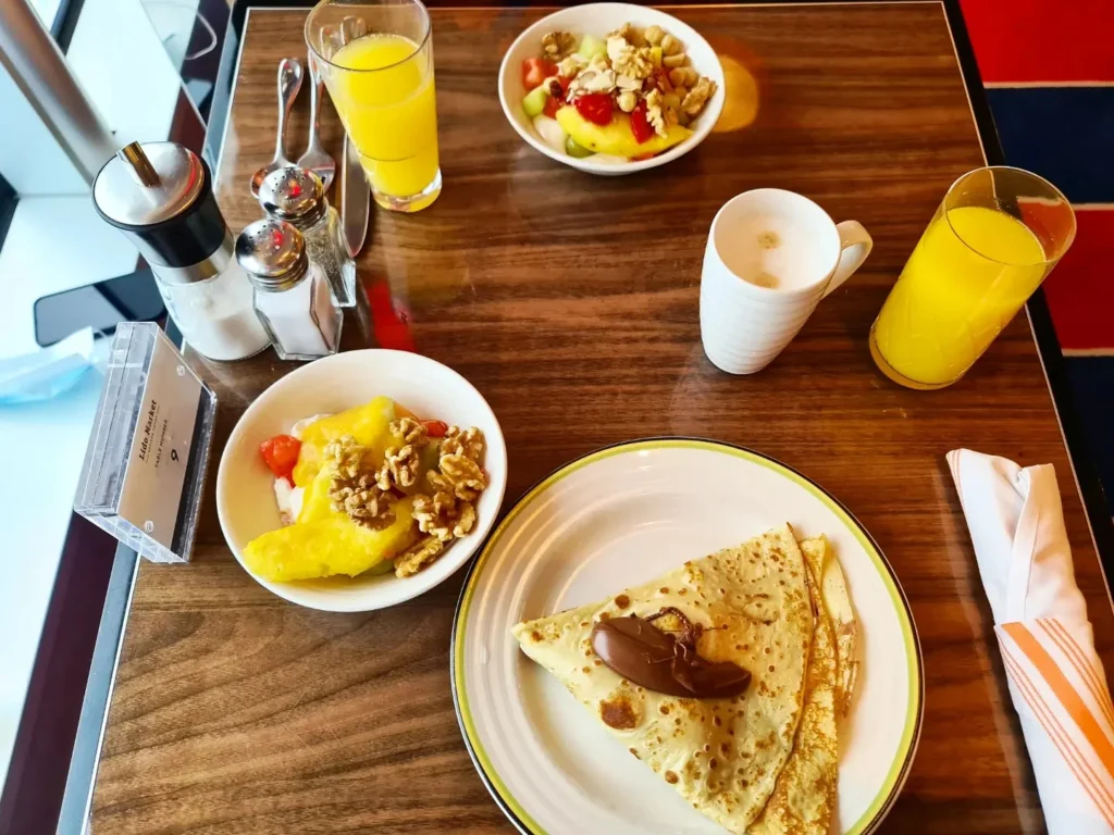 Cruising with Danny and Peter, Holland America Line, Koningsdam, Pacific Ocean, Sea Day | Passengers enjoying a tranquil Holland America sea day aboard a luxury cruise ship, participating in ocean voyage activities such as ukulele lessons, savoring gourmet dining at sea, and relaxing by the pool while overlooking the serene waters. The elegant ship provides panoramic ocean views and a perfect setting for a memorable Holland America Line experience. The day also includes presentations on maritime history, reflecting the ultimate luxury travel experience at sea.