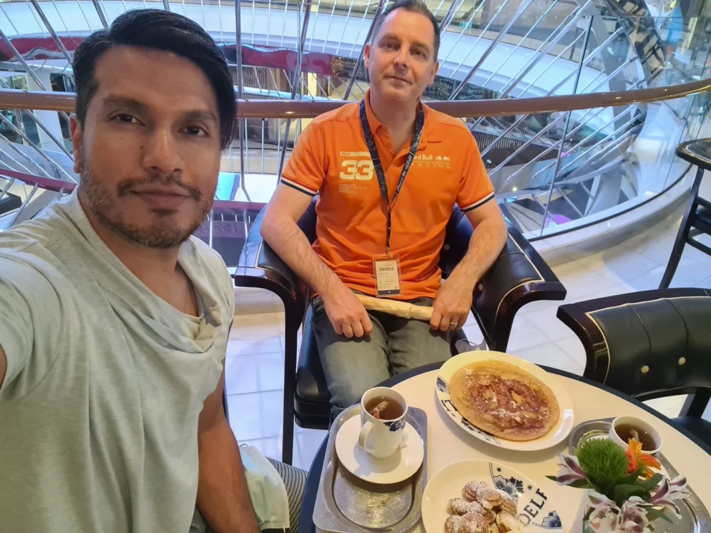 Cruising with Danny and Peter, Holland America Line, Koningsdam, Pacific Ocean, Sea Day | Passengers enjoying a tranquil Holland America sea day aboard a luxury cruise ship, participating in ocean voyage activities such as ukulele lessons, savoring gourmet dining at sea, and relaxing by the pool while overlooking the serene waters. The elegant ship provides panoramic ocean views and a perfect setting for a memorable Holland America Line experience. The day also includes presentations on maritime history, reflecting the ultimate luxury travel experience at sea.