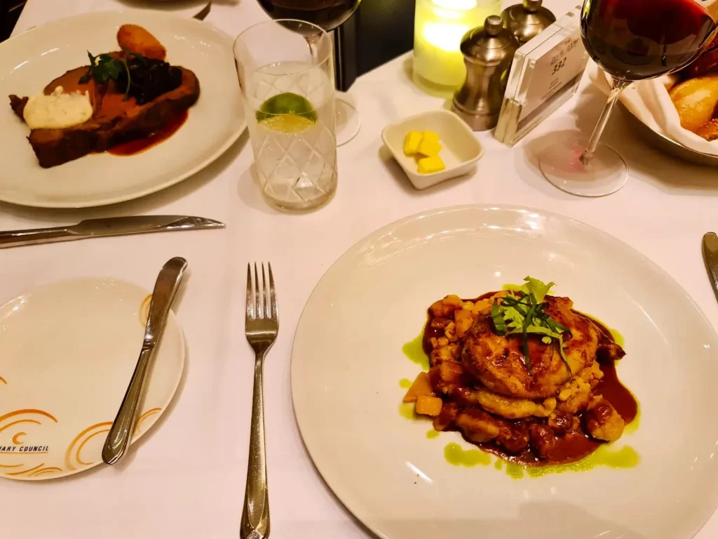 Cruising with Danny and Peter, Holland America Line, Koningsdam, Pacific Ocean, Sea Day | Passengers enjoying a tranquil Holland America sea day aboard a luxury cruise ship, participating in ocean voyage activities such as ukulele lessons, savoring gourmet dining at sea, and relaxing by the pool while overlooking the serene waters. The elegant ship provides panoramic ocean views and a perfect setting for a memorable Holland America Line experience. The day also includes presentations on maritime history, reflecting the ultimate luxury travel experience at sea.