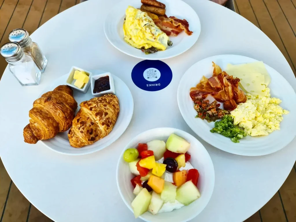 Cruising with Danny and Peter, Holland America Line, Koningsdam, Pacific Ocean, Sea Day | A stunning sunrise over the ocean during a Hawaiian cruise, showcasing the vibrant colors of the sky, a luxury cruise ship on calm waters, guests enjoying marine biology lectures, participating in ukulele lessons, and savoring delicious culinary experiences, embodying relaxation and adventure at sea in the beautiful Hawaiian Islands.