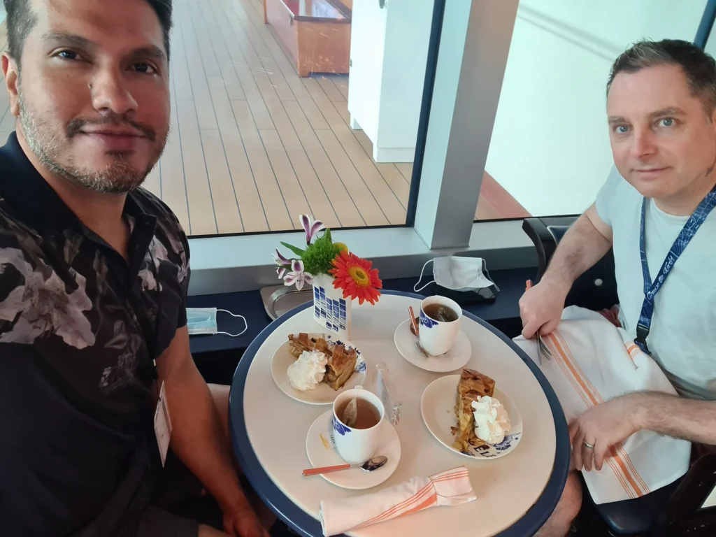 Cruising with Danny and Peter, Holland America Line, Koningsdam, Pacific Ocean, Sea Day | A stunning sunrise over the ocean during a Hawaiian cruise, showcasing the vibrant colors of the sky, a luxury cruise ship on calm waters, guests enjoying marine biology lectures, participating in ukulele lessons, and savoring delicious culinary experiences, embodying relaxation and adventure at sea in the beautiful Hawaiian Islands.