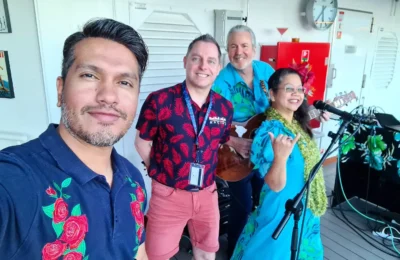 Cruising with Danny and Peter, Holland America Line, Koningsdam, Pacific Ocean, Sea Day | Group of travelers enjoying ukulele lessons on the deck of a cruise ship during an ocean voyage. Vibrant sunset over the sea, showcasing the essence of Hawaiian culture. Participants performing in a live music at sea event, celebrating their ukulele performances together, surrounded by the beauty of the ocean and the warmth of camaraderie.