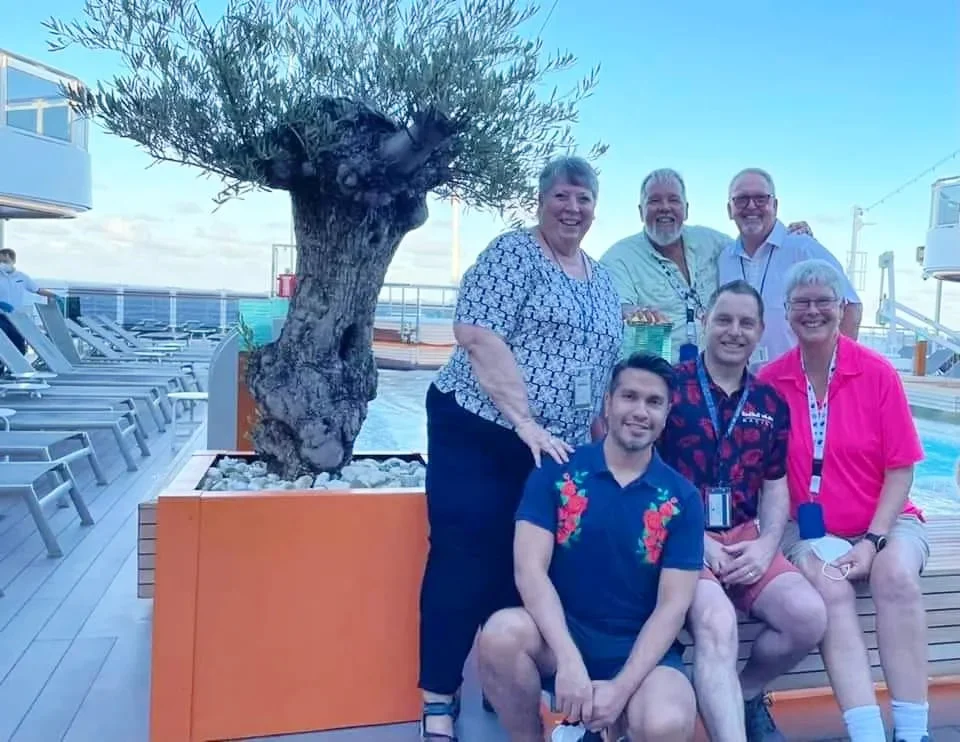 Cruising with Danny and Peter, Holland America Line, Koningsdam, Pacific Ocean, Sea Day | Group of travelers enjoying ukulele lessons on the deck of a cruise ship during an ocean voyage. Vibrant sunset over the sea, showcasing the essence of Hawaiian culture. Participants performing in a live music at sea event, celebrating their ukulele performances together, surrounded by the beauty of the ocean and the warmth of camaraderie.